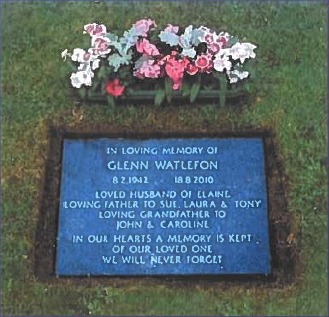 Council example of a flat granite memorial tablet with silver lettering, set into lawn, with a flower container behind it